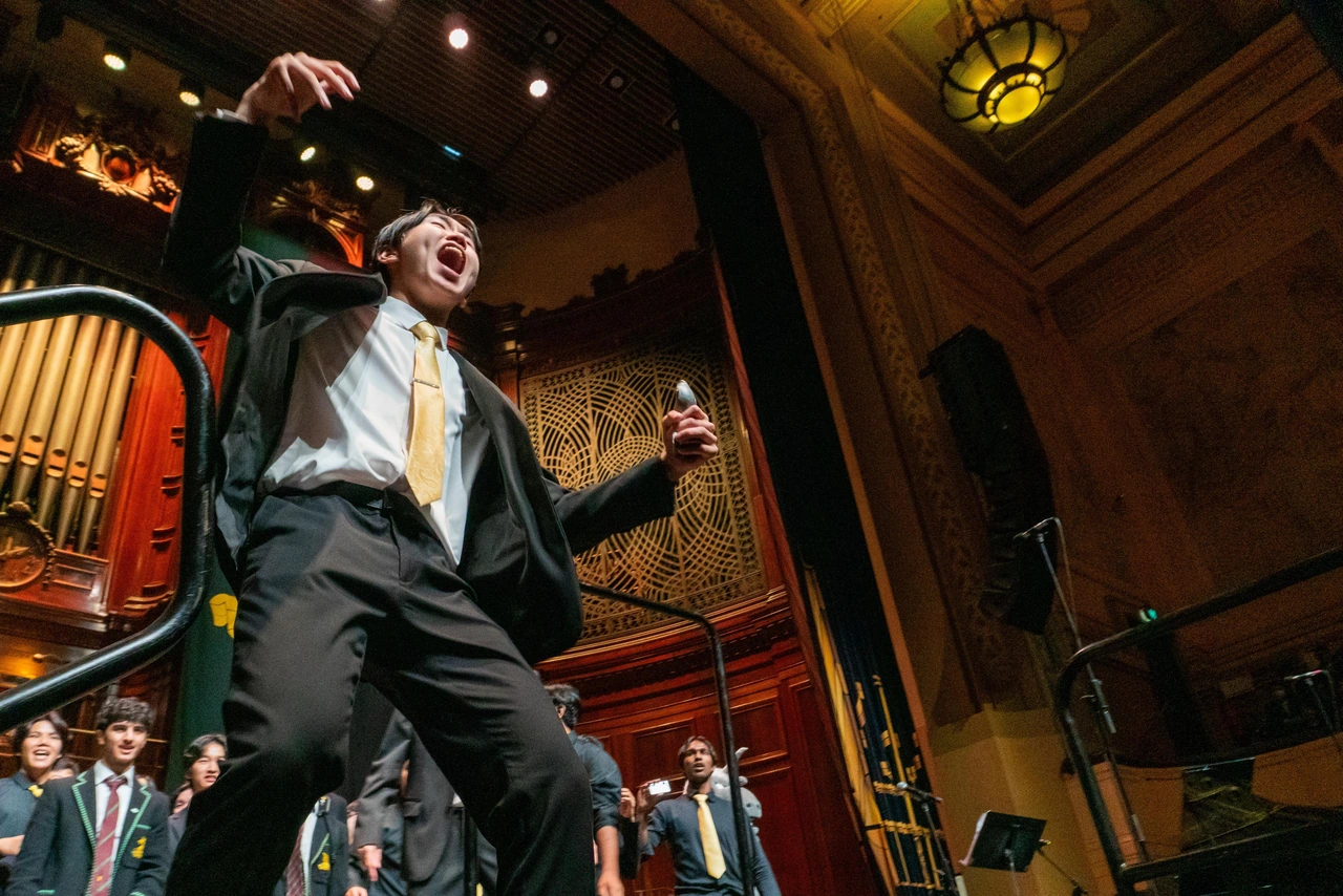 Isaac conducting with an expressive gesture in front of the Melbourne High School choir
