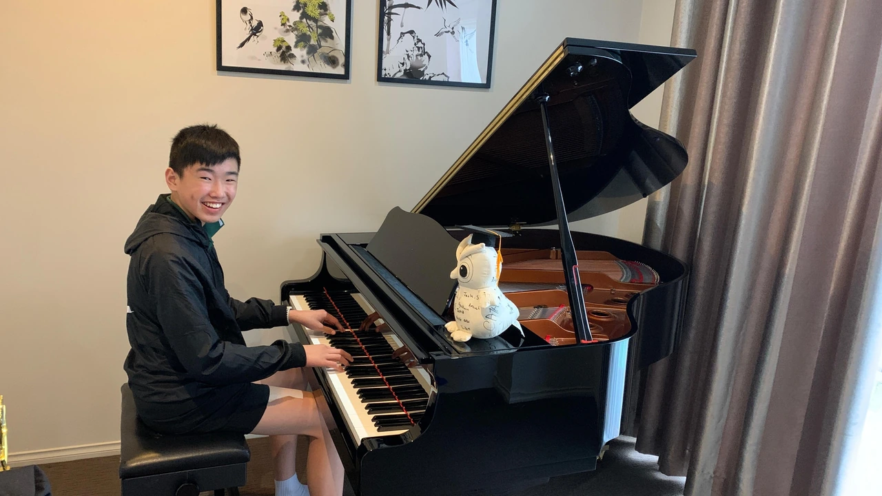 Isaac smiling at his Yamaha baby grand piano