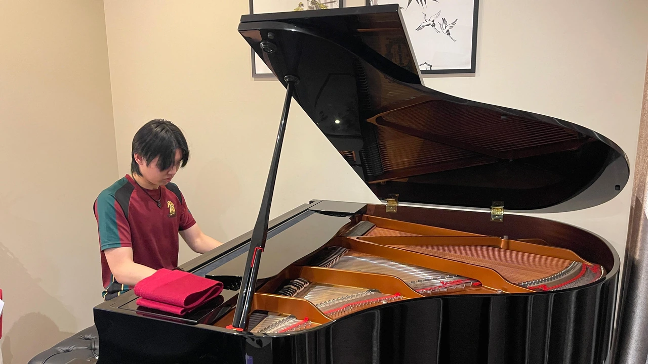 Isaac practising at his grand piano, with the lid open